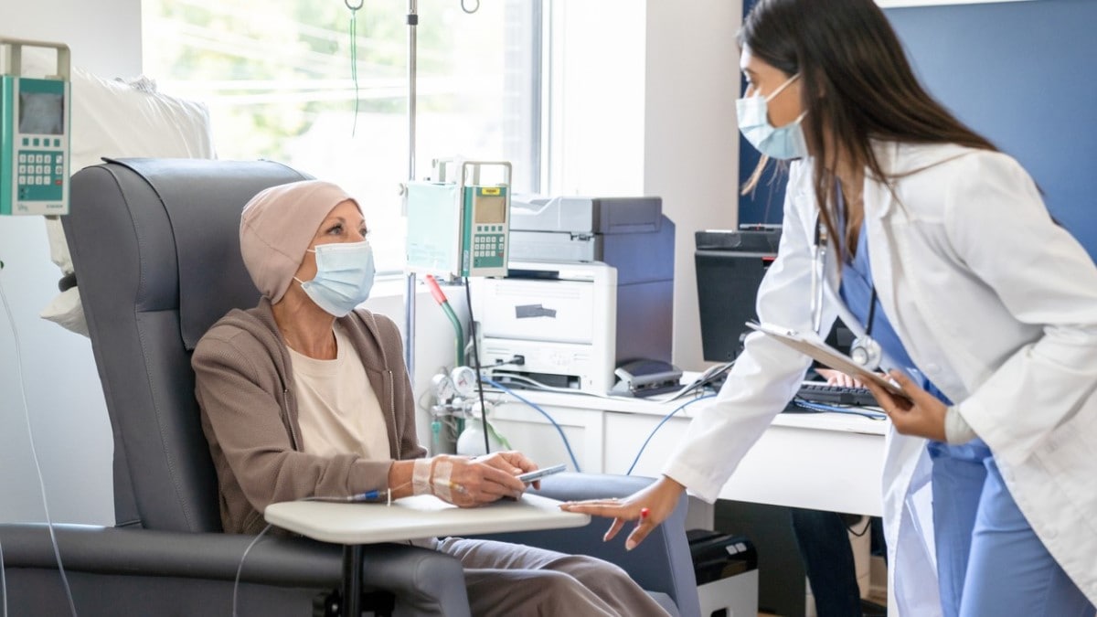 una enfermera hablando con una mujer recibiendo quimioterapia