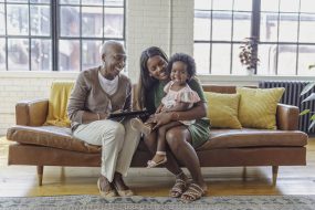 Two adults sitting on a couch with a small child.