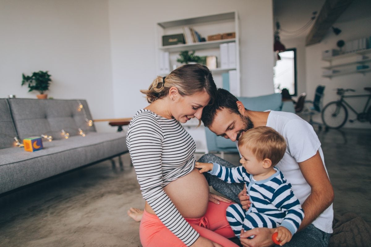 Parents with young child, the child touching mother's pregnant belly.