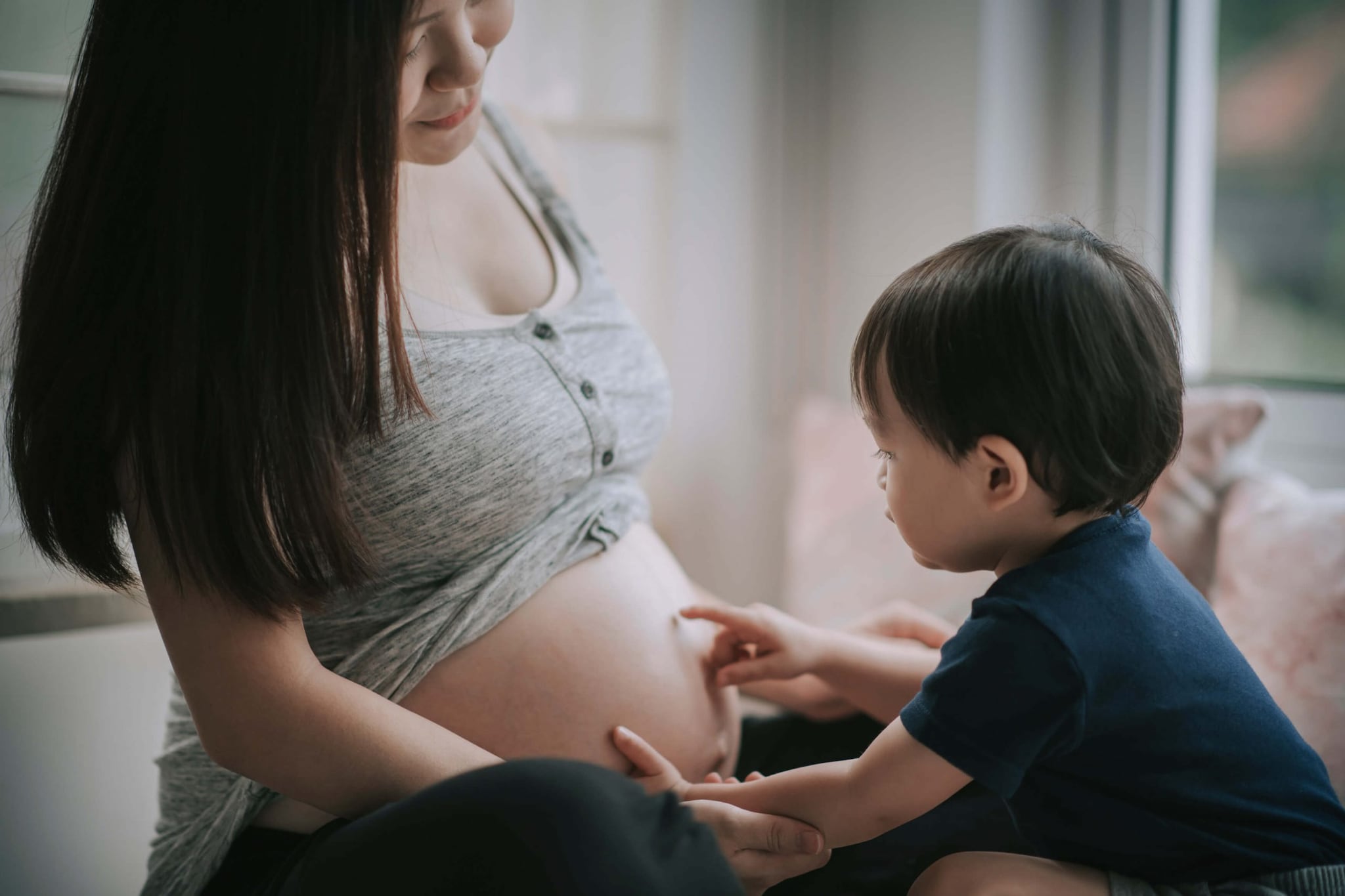 Pregnant woman with young child touching her belly