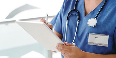 Cropped shot of an unrecognizable female surgical nurse making notes on a digital tablet will standing in the hallway of the hospital