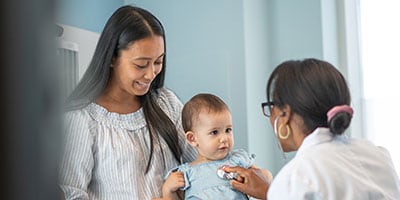 Female pediatrician checks heart of baby girl in medical appointment