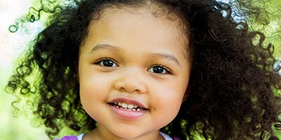 Toddler smiles while walking in the park on a sunny day