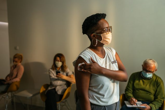 A vaccinated woman stands in a hospital waiting room.