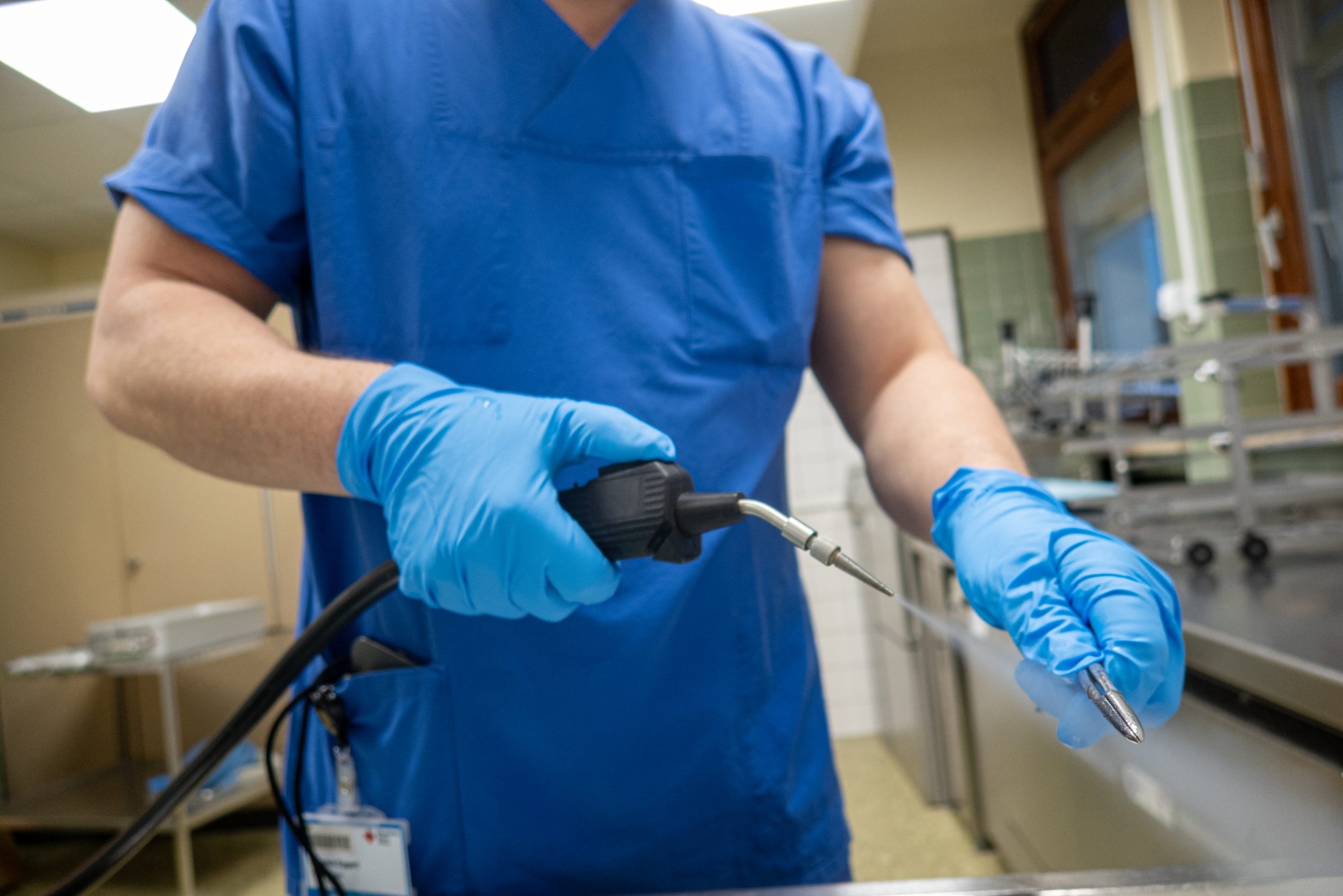 Health care professional using an instrument that shoots steam to sanitize something.