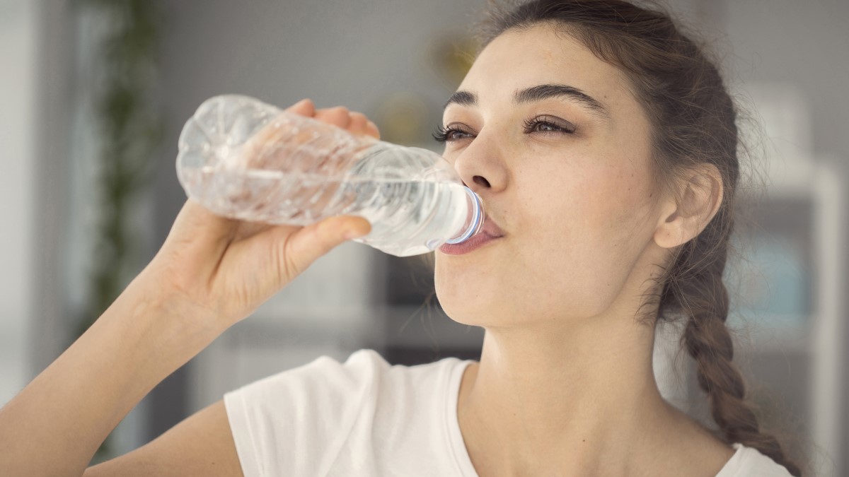 Woman drinking bottled water inside