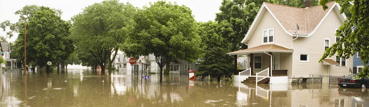 A street with homes on it that is flooded after a natural disaster.