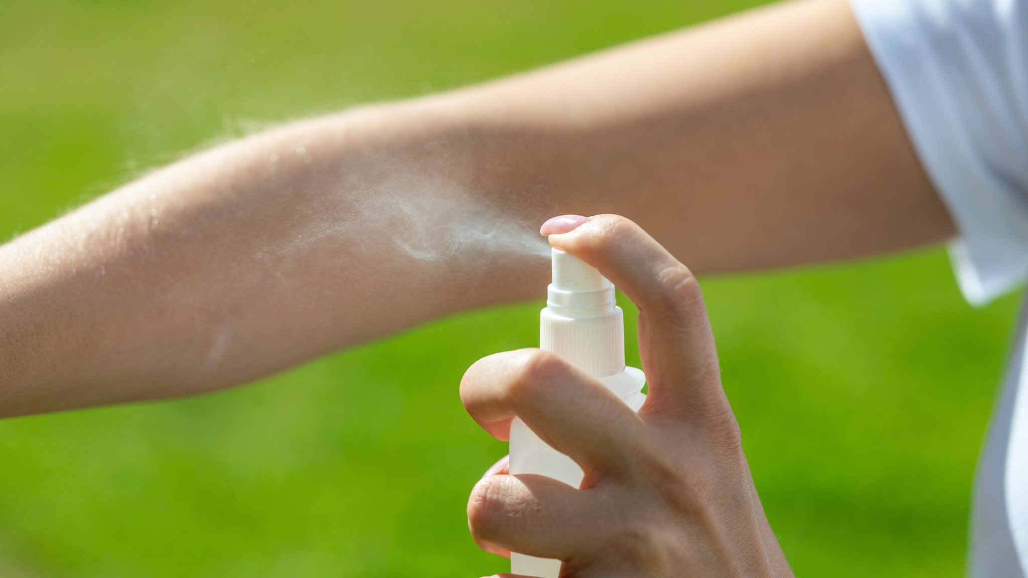 Person sparying insect repellent on their arm