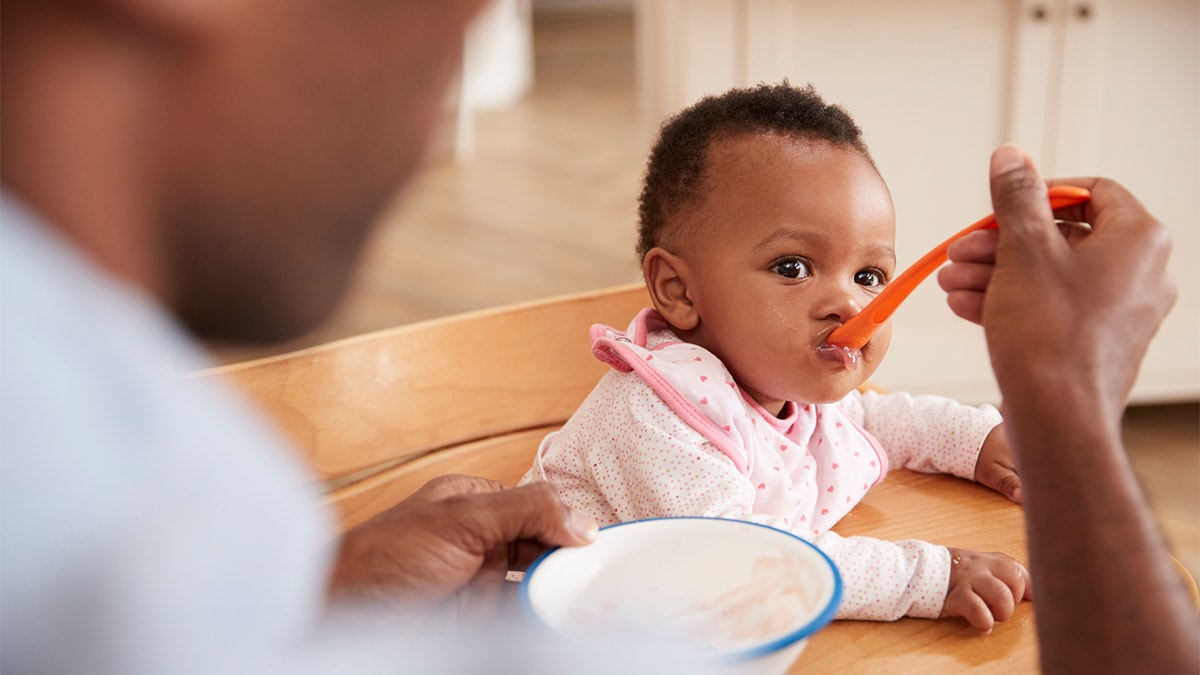 Baby eating food off a spoon.