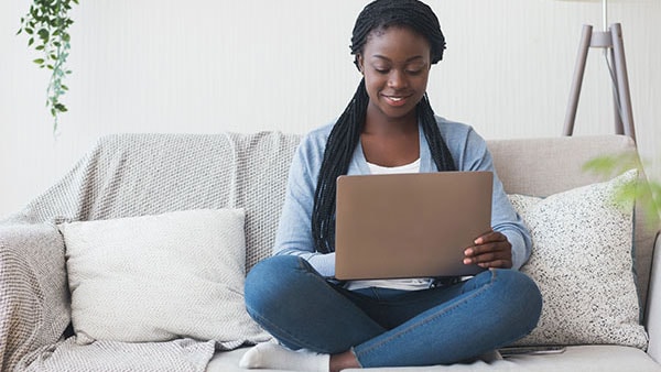 A female educator sitting on the sofa and using laptop.